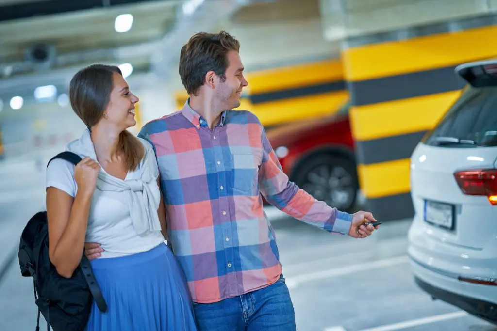 Adult couple in underground parking lot - Fusion Parking Happy and embraved man and woman locking their car in a parking garage to have parking safety to ensure secure parking.