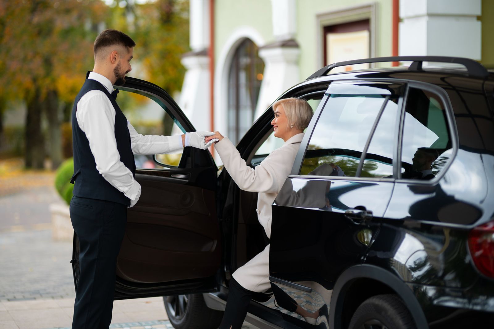 Male Valet helping a lady out of her car as a parking service that improves parking services.