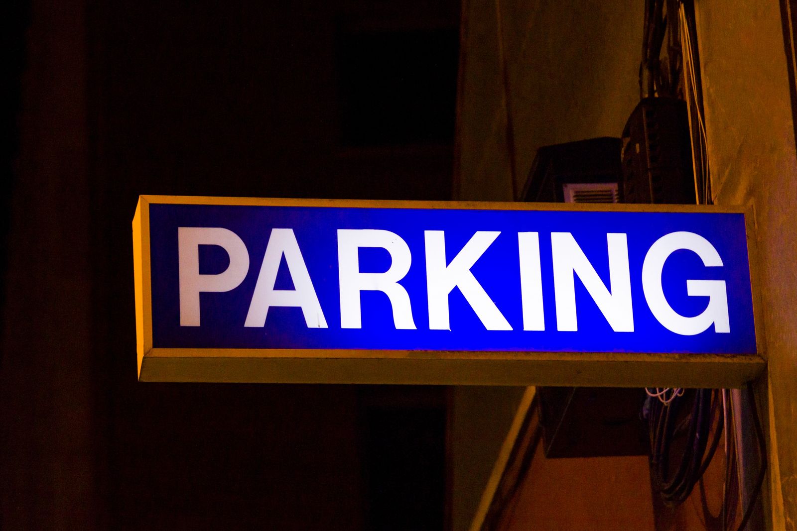 Sign on the side of a parking garage that shows parking services are provided.