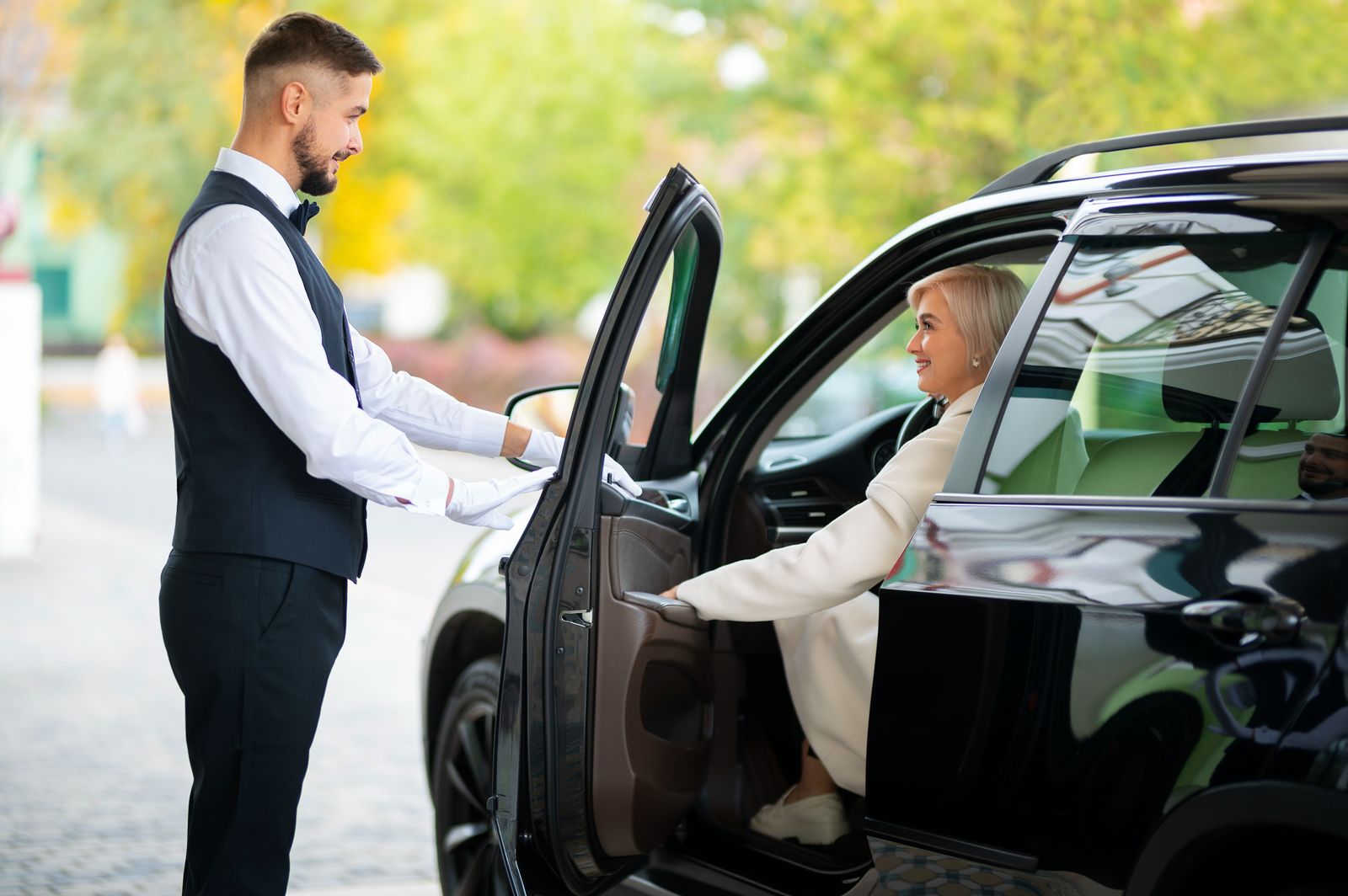 Valet parking service showing a valet helping a lady out of her black car.